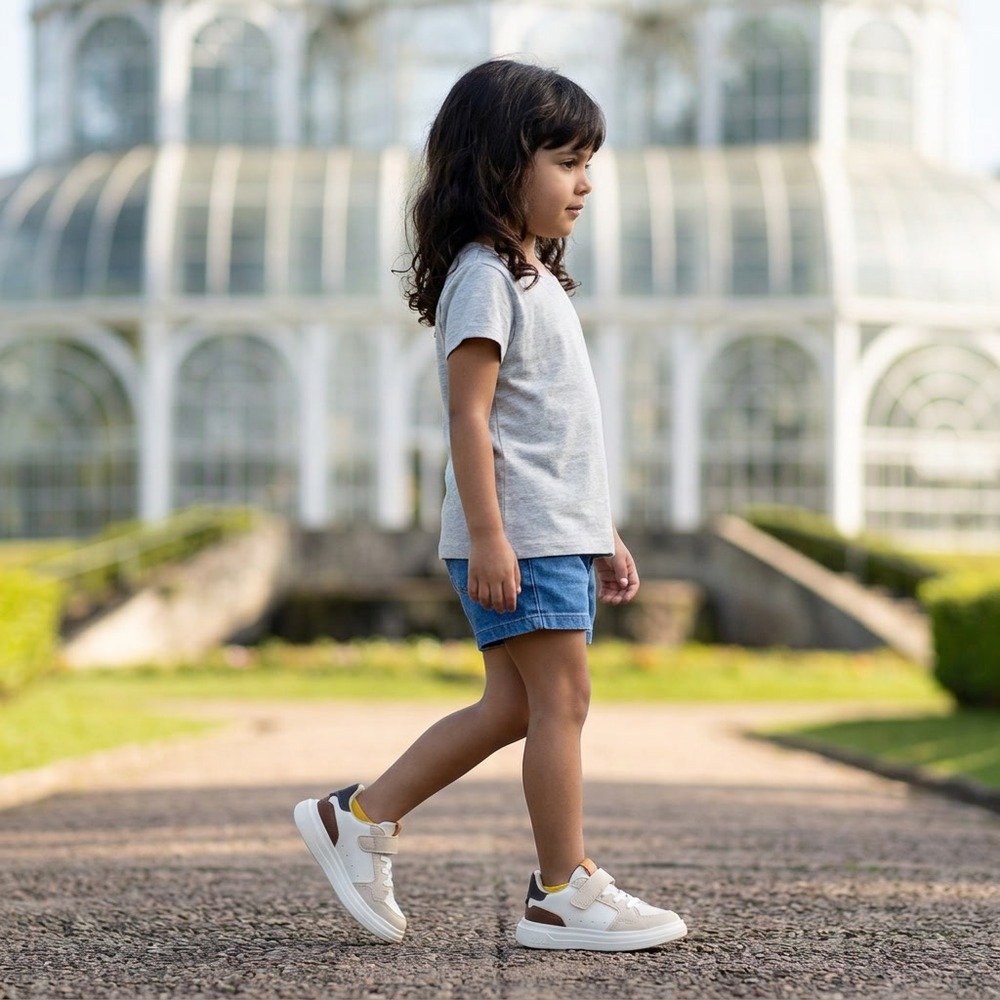Foto ilustrativa: Tênis Klin Infantil Unissex Capri Mini Off White, Whisky e Argila em uso, corpo inteiro